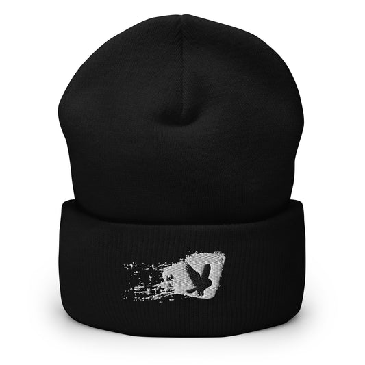 Black cuffed beanie with an embroidered design. Black bird flying with a white splattered background.