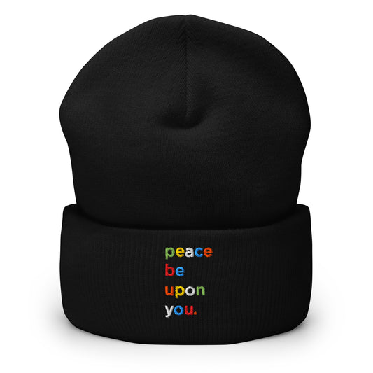 Black cuffed beanie with an embroidered design. Text says 'peace be upon you'. Each letter is a different color - green, yellow, white, blue, red.