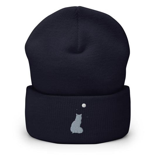 Navy blue cuffed beanie with an embroidered design. Light blue colored cat with a light yellow moon in sky.