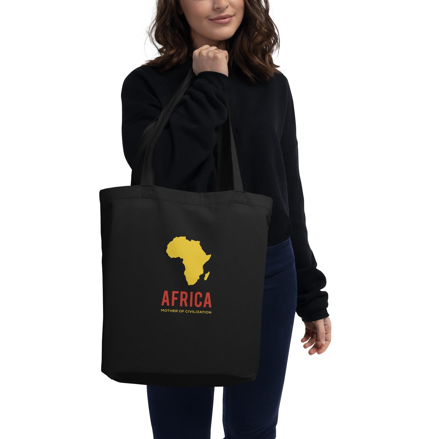 Woman holding a black totebag with yellow Africa shape and "Africa Mother of Civilization" written under in yellow and red text.