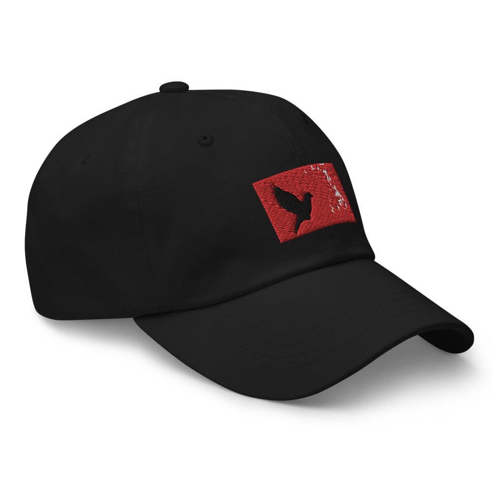 Black dad hat with an embroidered red rectangle and a black pigeon flying on it. Hat faceing it's right.