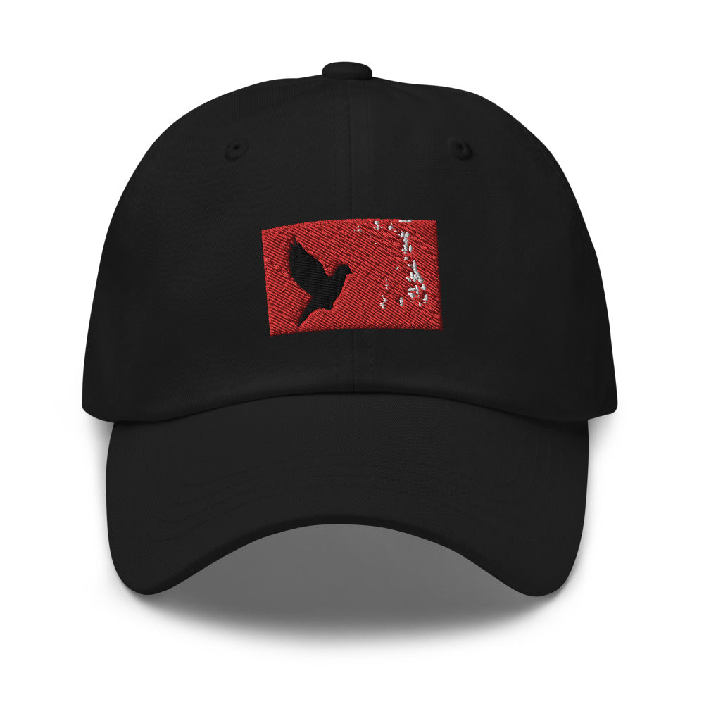 Black dad hat with an embroidered red rectangle and a black pigeon flying on it.